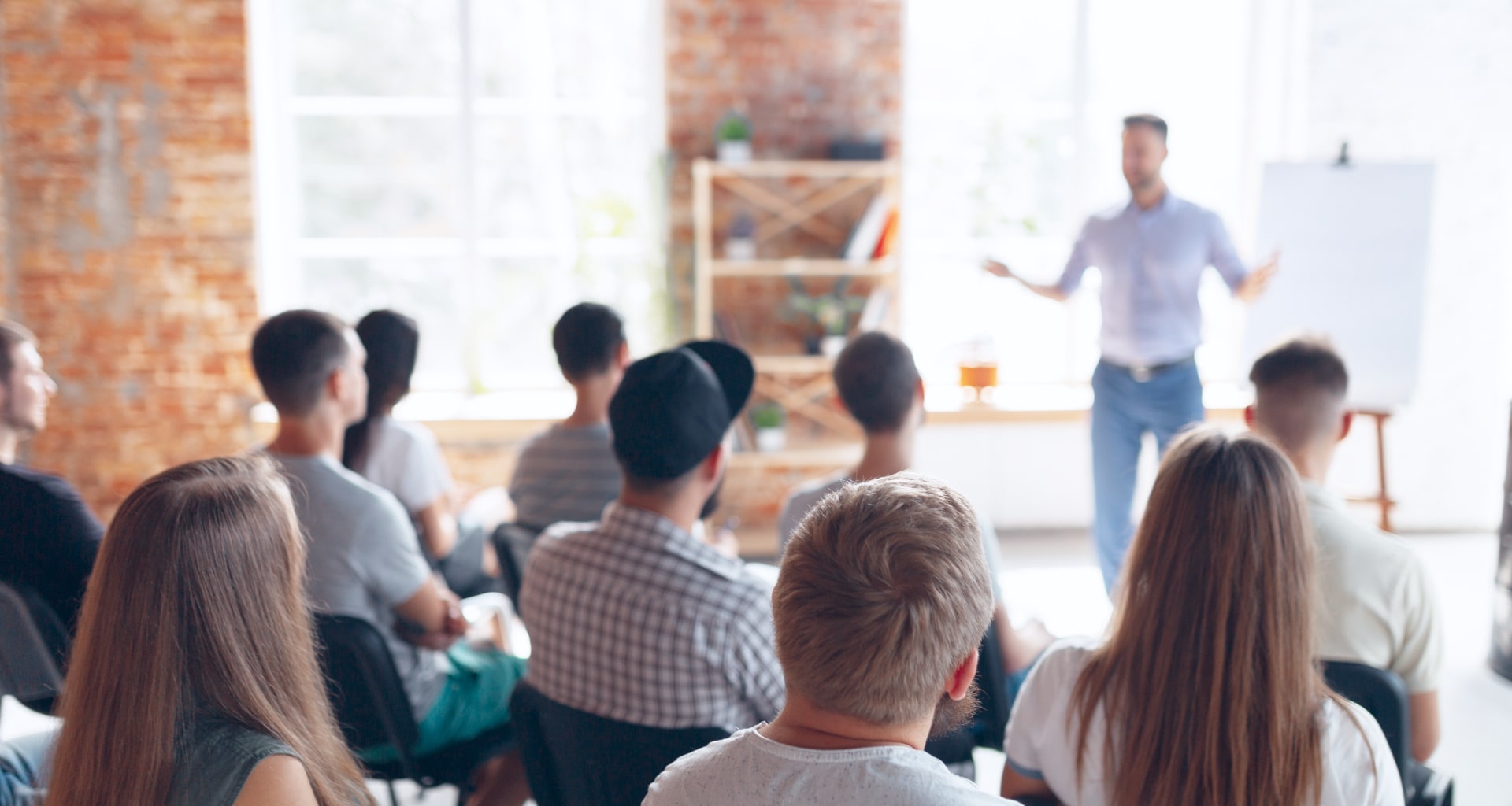 Business presentation in modern workspace with audience facing presenter.